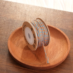 Macro detail of two-tone orange and blue hand-woven cotton thread on a cardboard spool