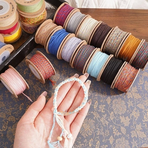 Macro view of colorful hand-woven cotton cords and DIY bracelet on wooden spools