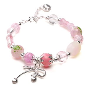 Detailed view of pink beaded DIY bracelet with silver bow pendant and heart charms