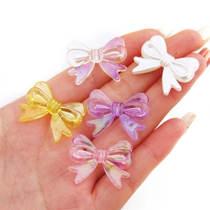 Colorful acrylic bow beads for DIY jewelry making displayed on a hand with glossy finish