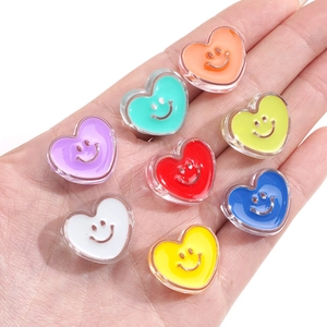 Macro shot of colorful acrylic heart beads with smiley faces held in a hand for DIY crafts