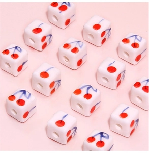 Macro view of 8mm square ceramic beads with hand-painted cherry patterns for DIY jewelry