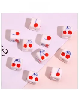 Detailed view of square ceramic beads with hand-painted cherry pattern for DIY jewelry