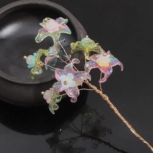 Macro shot of colorful AB acrylic flower charms with golden wire and bead detailing