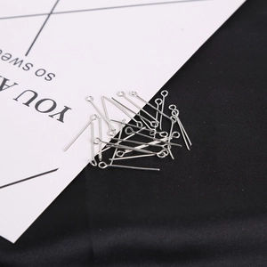 Macro shot of silver metal eye pins for DIY jewelry making on white card and black fabric