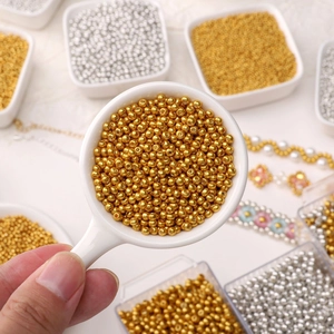 Gros plan de perles de rocaille dorées pour bijoux DIY présentées dans une petite cuillère
