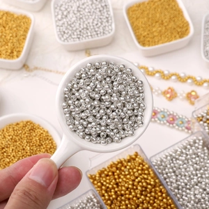 Perles de verre dorées et argentées pour bijoux DIY présentées sur une cuillère