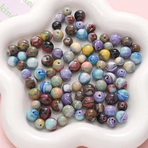 Gros plan de perles en résine colorées à motif marbré sur un plateau blanc décoratif