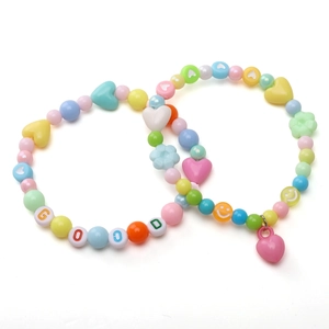 Détail de bracelets en perles DIY avec perles acryliques macaron et breloques cœur