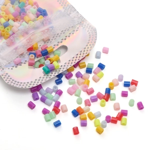 Perles en plastique colorées sortant d'un sachet holographique à fermeture éclair