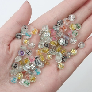 Handheld view of transparent acrylic alphabet beads with colorful glitter for DIY crafting