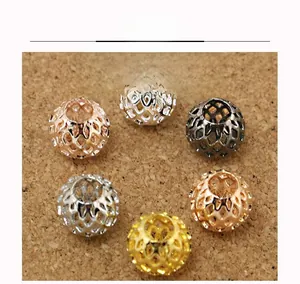 Close-up of hollowed tennis ball shaped metal beads in various plating colors for DIY