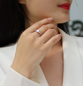 Detail of emerald-cut moissanite silver ring worn on hand with three-stone design