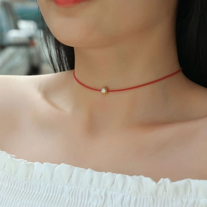 Dettaglio della collana in corda rossa con ciondolo in moissanite dorata su modella