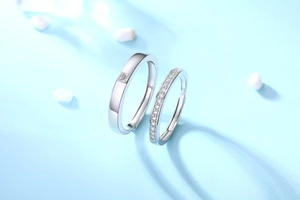 Close-up of S925 sterling silver couple rings with moissanite inlay on blue background