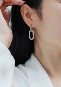 Close-up of S925 silver link earrings with pave-set moissanite on a female model