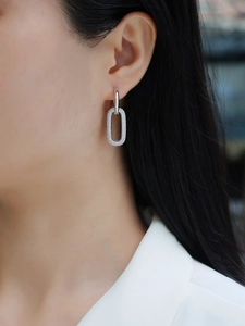 Detailed close-up of oval S925 silver earrings with full moissanite stones on a model