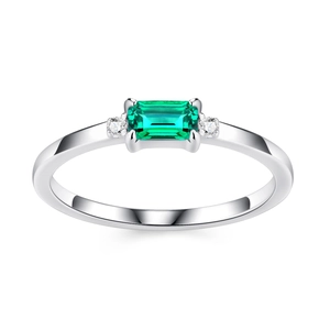Macro view of rectangular emerald cut green gemstone and side diamonds on silver ring