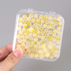 Detailed view of yellow and white gradient beads inside a clear plastic storage box