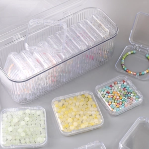 Detailed top view of clear plastic jewelry box organizer with beads and bracelets