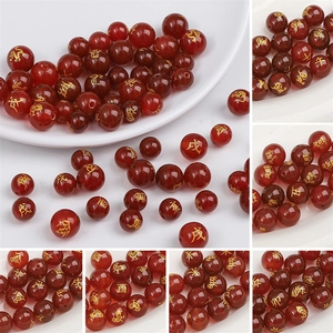 Detalle macro de cuentas de ágata roja con grabados zodiacales dorados para joyas
