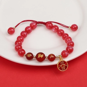 Detalle de cuentas de ágata roja con grabado del zodiaco dorado y colgante de la suerte