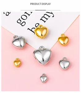 Polished gold and silver heart-shaped pendants in various sizes on a pink background