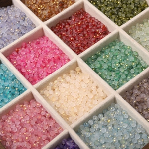 Close-up of matte frosted glass beads with gold foil details in a grid jewelry box