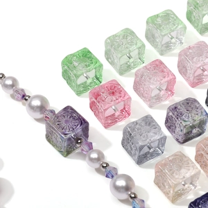 Macro detail of cube-shaped carved glass beads in pastel colors for DIY jewelry making