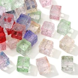 Macro view of transparent colorful glass cube beads with embossed floral patterns for DIY