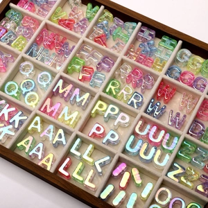 Macro detail of iridescent acrylic alphabet beads organized in a wooden divider tray