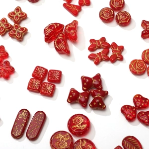 Detailed close-up of red glass beads with gold patterns for DIY jewelry making