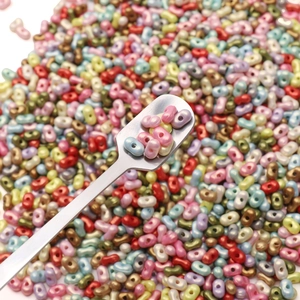 Macro shot of colorful peanut shaped glass beads on a metal spoon for DIY jewelry making