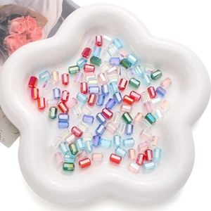 Macro view of colorful faceted rectangle glass crystal beads in a white petal tray