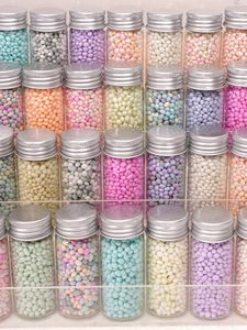 Macro di perline colorate in vasetti di vetro con tappi a vite argento per gioielli