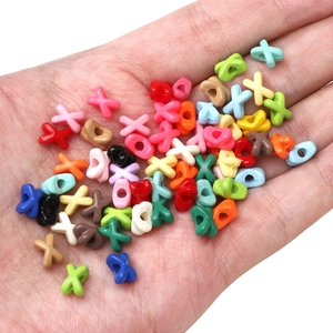 Colorful X-shaped acrylic beads held in hand for DIY jewelry making and bracelet crafts