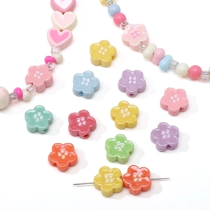 Dettaglio di perline acriliche colorate a forma di fiori e cuori per gioielli DIY