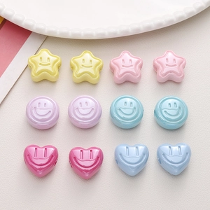 Dettaglio di perline in acrilico con faccina sorridente a forma di stella e cuore per gioielli