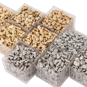 Macro shot of silver and gold metal charms in a plastic storage box for DIY jewelry