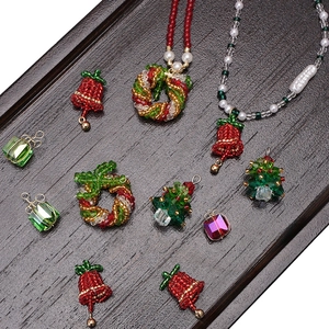Flat lay of handmade Christmas beaded jewelry including trees and wreaths on wooden tray