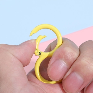 Yellow S-shaped alloy keychain clip with spring mechanism shown in hand for easy use
