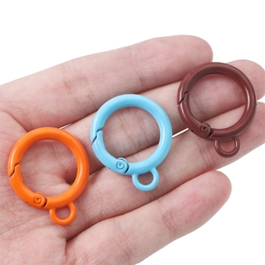 Colorful alloy spring O-rings in orange, blue, and brown held in palm for size scale