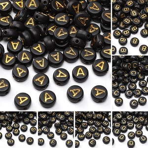 Macro shot of 4x7mm black acrylic flat round beads with gold engraved letters for DIY crafts