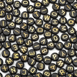 Macro shot of 4x7mm black acrylic flat round beads with gold alphabet letters for DIY jewelry