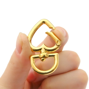 Detail of a heart-shaped gold alloy swivel lobster clasp held in hand with rotating D-ring