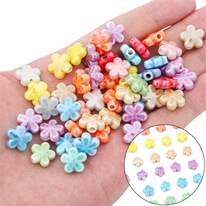 Colorful floral ceramic beads in hand showing vibrant five-petal flower charms for DIY jewelry