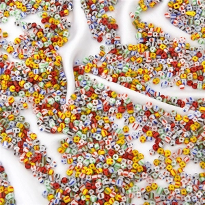 Macro shot of colorful striped glass seed beads for DIY jewelry making on white silk