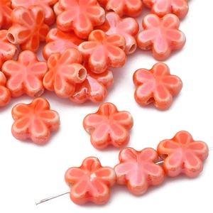 Detailed macro of orange ceramic five-petal flower beads for DIY jewelry making