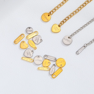 Détail macro de pendentifs en acier 316L et de chaînes d'extension en finitions or et argent
