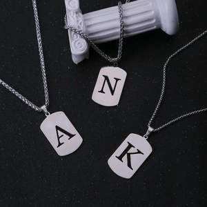 Detailopname van geborstelde roestvrijstalen dog tag hangers met holle letters N A K details